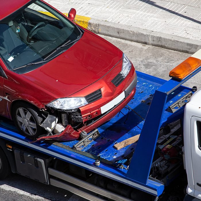 Crashed car loaded on a tow truck. Damage vehicle after crash accident on city street